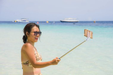 Deniz suyu selfie fotoğrafını cep telefonu kamera ile Cennet plaj üzerinde eğleniyor genç güzel ve mutlu Asyalı Çinli kadın