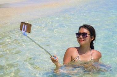 Deniz suyu selfie fotoğrafını cep telefonu kamera ile Cennet plaj üzerinde eğleniyor genç güzel ve mutlu Asyalı Çinli kadın