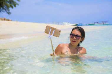 Deniz suyu selfie fotoğrafını cep telefonu kamera ile Cennet plaj üzerinde eğleniyor genç güzel ve mutlu Asyalı Çinli kadın