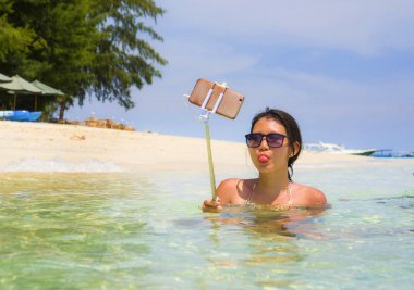 Deniz suyu selfie fotoğrafını cep telefonu kamera ile Cennet plaj üzerinde eğleniyor genç güzel ve mutlu Asyalı Çinli kadın