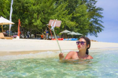 Deniz suyu selfie fotoğrafını cep telefonu kamera ile Cennet plaj üzerinde eğleniyor genç güzel ve mutlu Asyalı Çinli kadın