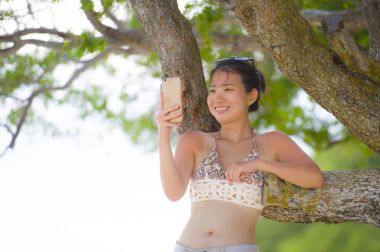 tatlı ve güzel Asyalı kadın cep telefonuyla internet sosyal medya metin mutlu gülümseyerek için selfie fotoğraf çekimi