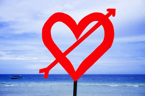 Isolated post signal with red love heart and arrow at beach on a blue sea and sky background in Valentines day and romance concept — Stock Photo, Image