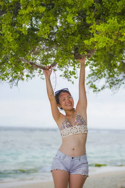 Wanita Cina yang bahagia memegang cabang pohon di pantai tropis tersenyum gembira bersenang-senang dalam liburan musim panas — Stok Foto