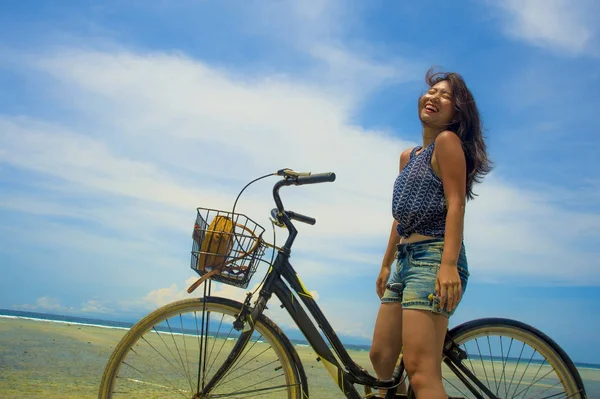 年轻漂亮和快乐的亚洲华人女孩骑着老式自行车在沙滩上欢笑和微笑欢快和自由有乐趣在自行车旅行 — 图库照片