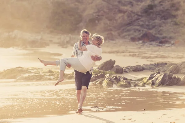 Encantador casal maduro sênior em seus 60 ou 70 anos aposentado andando feliz e relaxado na praia costa do mar em envelhecimento romântico juntos — Fotografia de Stock