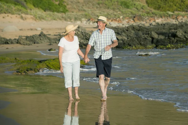 Encantador casal maduro sênior em seus 60 ou 70 anos aposentado andando feliz e relaxado na praia costa do mar em envelhecimento romântico juntos — Fotografia de Stock