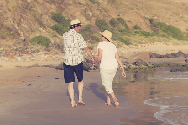 Encantador casal maduro sênior em seus 60 ou 70 anos aposentado andando feliz e relaxado na praia costa do mar em envelhecimento romântico juntos — Fotografia de Stock