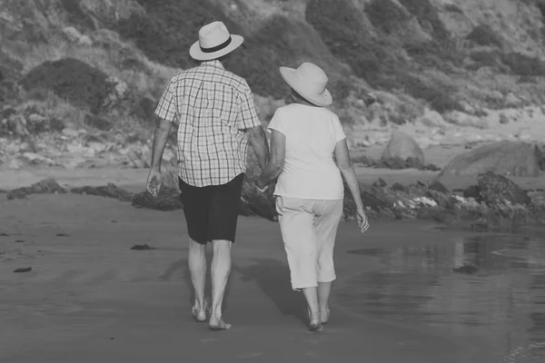 Lovely senior mature couple on their 60s or 70s retired walking happy and relaxed on beach sea shore in romantic aging together — Stock Photo, Image