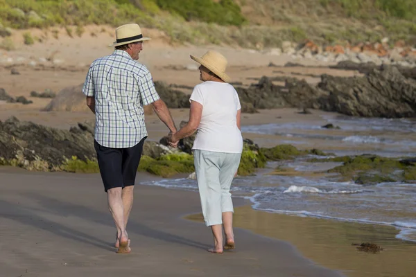 Encantador casal maduro sênior em seus 60 ou 70 anos aposentado andando feliz e relaxado na praia costa do mar em envelhecimento romântico juntos — Fotografia de Stock