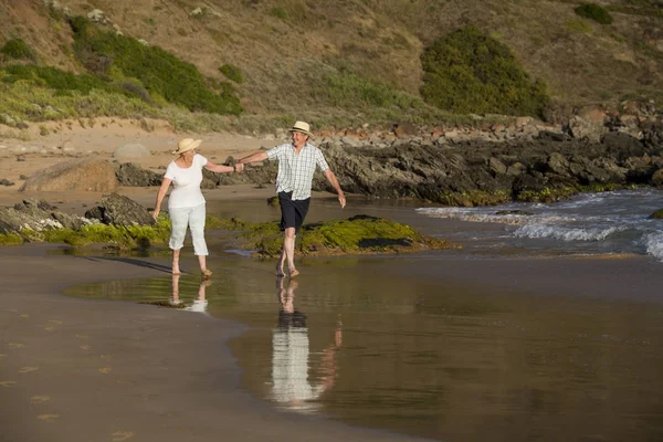 Lovely senior mature couple on their 60s or 70s retired walking happy and relaxed on beach sea shore in romantic aging together — Stock Photo, Image