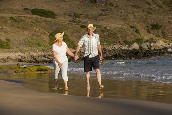 Encantador casal maduro sênior em seus 60 ou 70 anos aposentado andando feliz e relaxado na praia costa do mar em envelhecimento romântico juntos — Fotografia de Stock