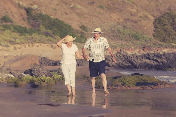 Encantador casal maduro sênior em seus 60 ou 70 anos aposentado andando feliz e relaxado na praia costa do mar em envelhecimento romântico juntos — Fotografia de Stock