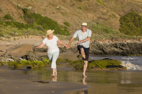 Encantador casal maduro sênior em seus 60 ou 70 anos aposentado andando feliz e relaxado na praia costa do mar em envelhecimento romântico juntos — Fotografia de Stock