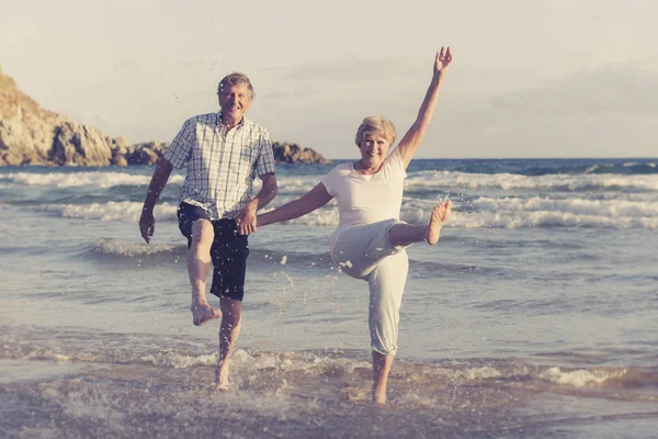 Encantador casal maduro sênior em seus 60 ou 70 anos aposentado andando feliz e relaxado na praia costa do mar em envelhecimento romântico juntos — Fotografia de Stock