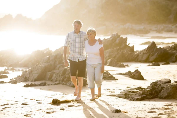 Encantador casal maduro sênior em seus 60 ou 70 anos aposentado andando feliz e relaxado na praia costa do mar em envelhecimento romântico juntos — Fotografia de Stock