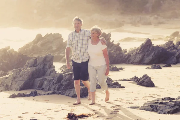 Encantador casal maduro sênior em seus 60 ou 70 anos aposentado andando feliz e relaxado na praia costa do mar em envelhecimento romântico juntos — Fotografia de Stock