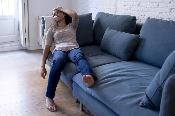 Young attractive latin woman lying at home living room couch tired and worried suffering depression feeling sad and desperate with a headache — Stock Photo, Image