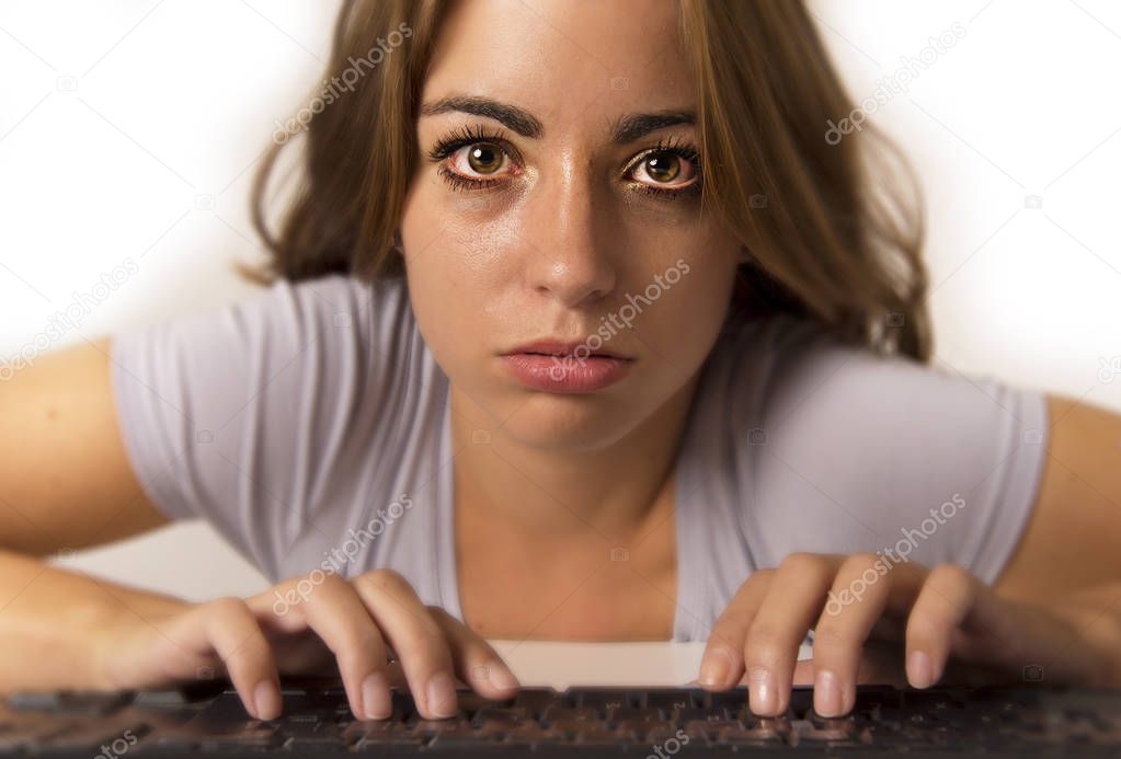 attractive student girl or working woman sitting at computer desk in stress with tired red eyes after long hours working looking at the screen