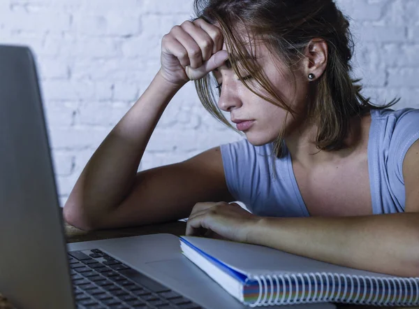 Müde Studentin arbeitet mit Schreibblock am Laptop und fühlt sich frustriert und erschöpft, wenn sie spät in der Nacht für die Prüfung lernt — Stockfoto