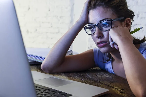 Müde Studentin arbeitet mit Schreibblock am Laptop und fühlt sich frustriert und erschöpft, wenn sie spät in der Nacht für die Prüfung lernt — Stockfoto