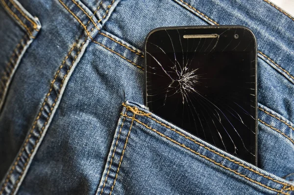 Mobile phone broken and cracked touch screen in the back pocket of jeans denim trousers in accident and careless concept — Stock Photo, Image
