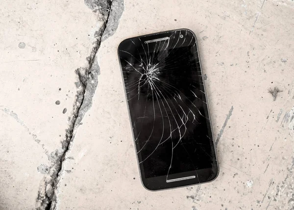 Dispositivo mobile graffiato e rotto crepa touch screen abbandonato su strada terra di cemento in riparazione e risolvere il concetto di servizio di smart phone — Foto Stock