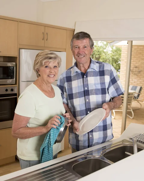 Senior beautiful middle age couple around 70 years old smiling happy at home kitchen washing the dishes looking sweet together — Stock Photo, Image