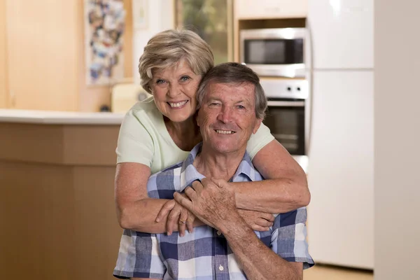 Senior hermosa pareja de mediana edad alrededor de 70 años sonriendo feliz juntos en casa cocina buscando dulce en concepto de marido y mujer de por vida — Foto de Stock