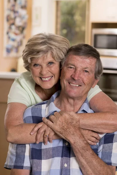 Senior hermosa pareja de mediana edad alrededor de 70 años sonriendo feliz juntos en casa cocina buscando dulce en concepto de marido y mujer de por vida — Foto de Stock