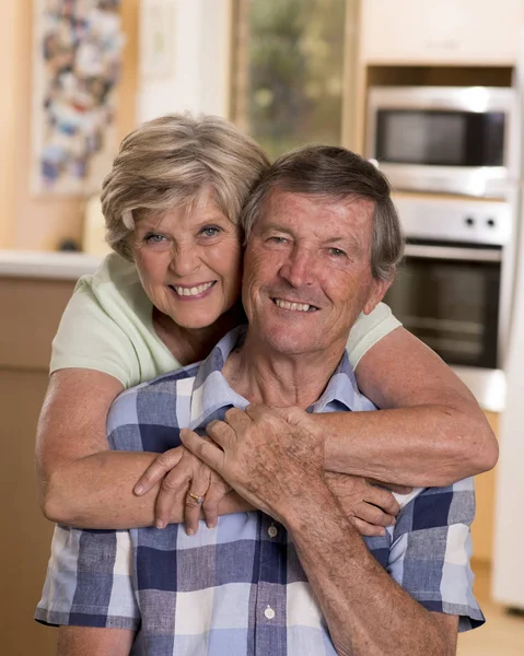 Senior hermosa pareja de mediana edad alrededor de 70 años sonriendo feliz juntos en casa cocina buscando dulce en concepto de marido y mujer de por vida — Foto de Stock