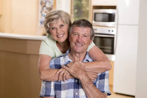 Senior hermosa pareja de mediana edad alrededor de 70 años sonriendo feliz juntos en casa cocina buscando dulce en concepto de marido y mujer de por vida — Foto de Stock