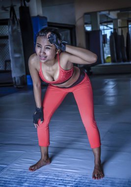Genç bitkin ve yorgun terli Asyalı kadın nefes ve zor eğitim fitness egzersiz yaptıktan sonra aşağı soğutma spor giyim 