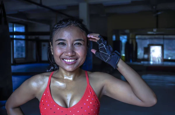 Портрет счастливой красивой и потной молодой азиатки в спортивной одежде, улыбающейся расслабленной в спортзале додзё после тренировки — стоковое фото