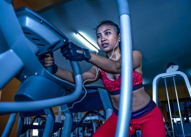 eliptik pedal makine dişli yoğun egzersiz egzersiz kullanarak spor salonunda sert eğitim genç seksi ve terli Asyalı kadın