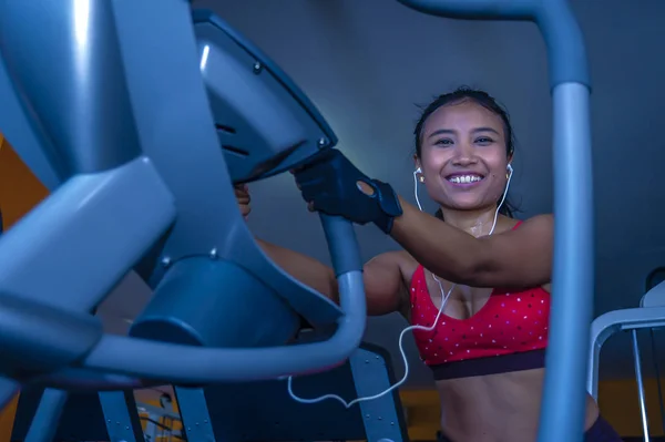 Joven sexy y sudorosa mujer asiática entrenando duro en el gimnasio usando equipo de máquina de pedaleo elíptico en ejercicio intenso — Foto de Stock