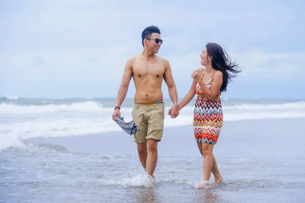 young beautiful Asian Chinese couple walking together on the bea