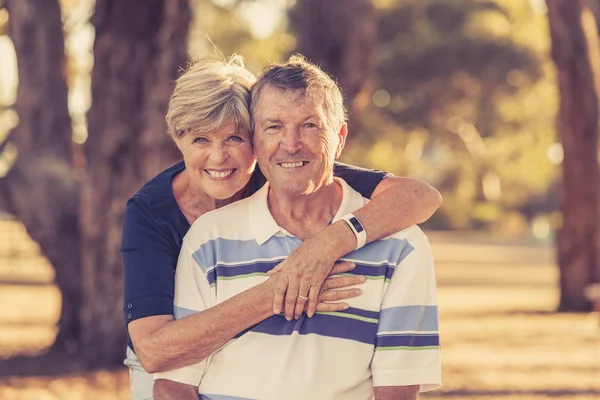 Εκλεκτής ποιότητας φίλτρο πορτρέτο της αμερικανικής senior όμορφο και ευτυχισμένο ζευγάρι περίπου 70 ετών δείχνει αγάπη και στοργή χαμογελώντας μαζί στο πάρκο — Φωτογραφία Αρχείου