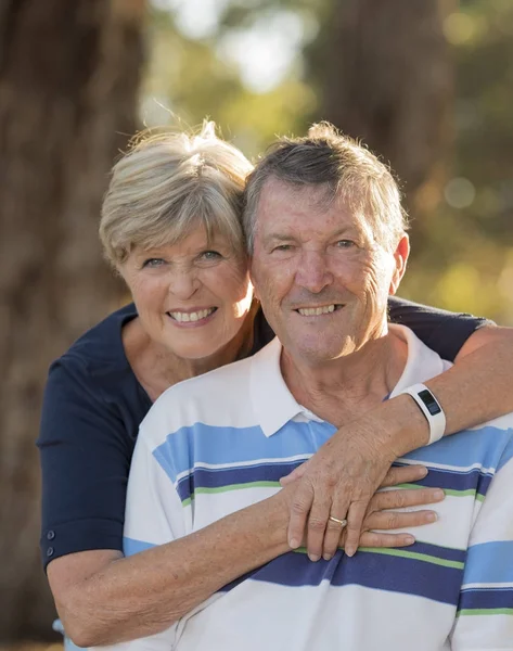 Vertical retrato de americano senior hermosa y feliz pareja madura alrededor de 70 años de edad mostrando el amor y el afecto sonriendo juntos en el parque — Foto de Stock