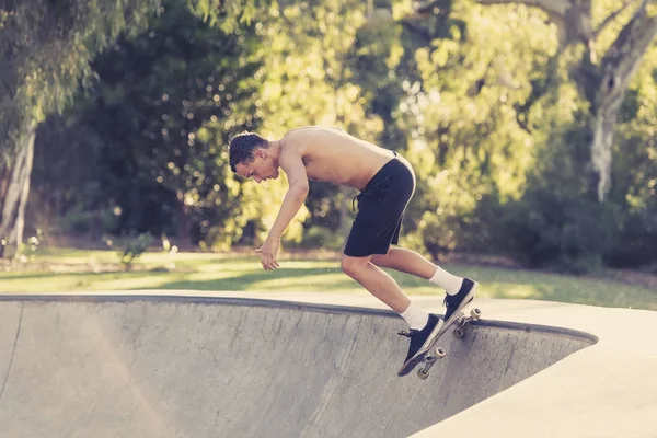 Pemuda Amerika dengan tubuh telanjang berlatih skate board radikal melompat dan menikmati trik dan stunts di beton setengah jalur skating pipa — Stok Foto