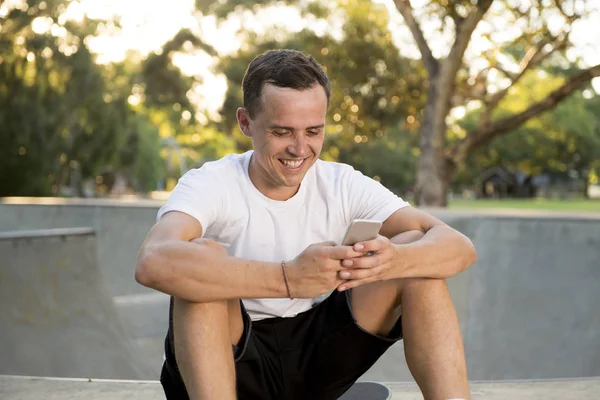 Amerikan eğitim oturumu cep telefonuyla internet sosyal medya metin gönderme yatılı spor sonrası paten kurulu üzerinde oturan 30'lu dostum — Stok fotoğraf