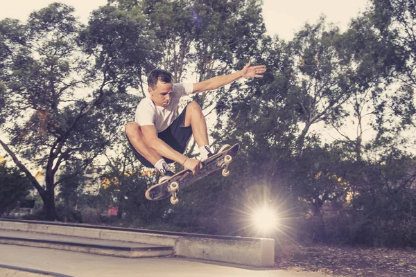 Uomo praticare skate board radicale salto e godendo di trucchi e acrobazie in pista di pattinaggio mezzo tubo di cemento nello sport e stile di vita sano — Foto Stock