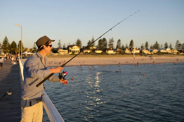 Junge attraktive und glückliche Mann in Hemd und Hut Angeln am Strand Meer Dock mit Fischstraße genießen am Wochenende Hobby in den Ferien — Stockfoto