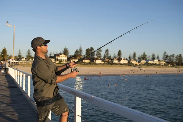 Junge attraktive und glückliche Mann in Hemd und Hut Angeln am Strand Meer Dock mit Fischstraße genießen am Wochenende Hobby in den Ferien — Stockfoto