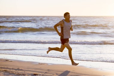 atletik zinde ve güçlü runner çalışan deniz kıyısında günbatımı Beach'te yaz ve fitness egzersiz spor ve sağlıklı yaşam konusunda eğitim dostum 