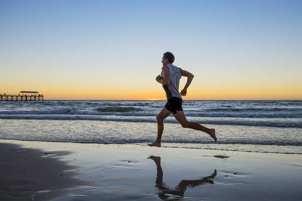 Спортивний одяг і сильний бігун тренування на пляжі літнього заходу сонця на березі моря біг і фітнес тренування в спорті і здоровий спосіб життя — стокове фото