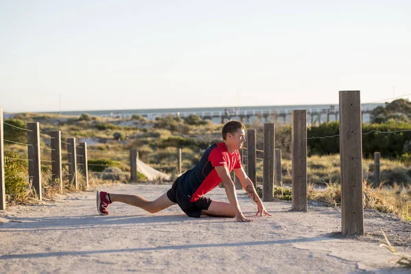 Jeune homme blond caucasien attrayant sur sa trentaine étirant la jambe dans l'exercice d'échauffement avant de courir séance d'entraînement dans l'entraînement sportif et mode de vie sain — Photo