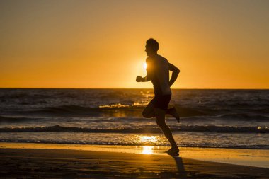 siluet genç dinamik atlet runner adamla güçlü beden eğitim Spor sağlıklı ve fitness kavramı içinde çıplak ayakla çalışan yaz günbatımı plaj üzerinde uygun