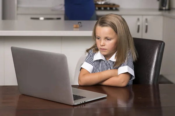 Niña de 6 a 8 años de edad sentado en casa cocina disfrutando con el ordenador portátil concentrado viendo películas de dibujos animados de Internet — Foto de Stock