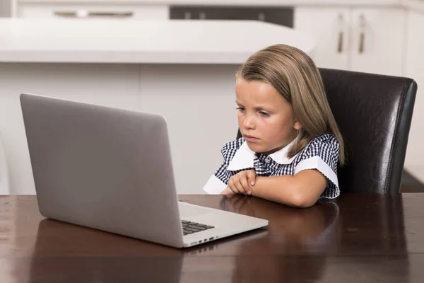 Niña de 6 a 8 años de edad sentado en casa cocina disfrutando con el ordenador portátil concentrado viendo películas de dibujos animados de Internet — Foto de Stock